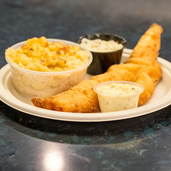 Fried fish with mac and cheese, tartar sauce, and coleslaw on a white plate.