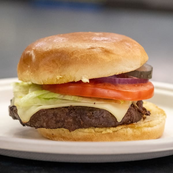 A Rosie's Corner Take Out Restaurant burger with cheese, lettuce, tomato, onion, and pickles.